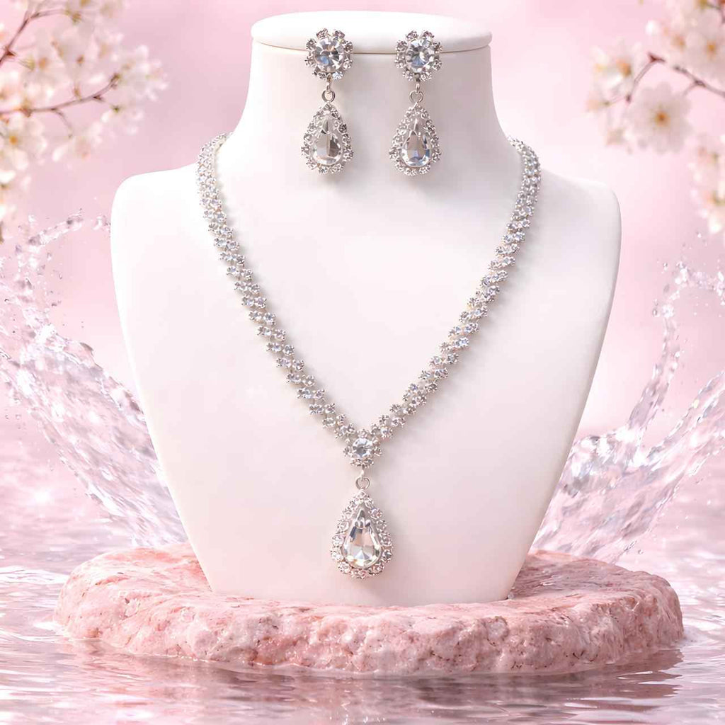 Diamond teardrop necklace with matching drop earrings on white display