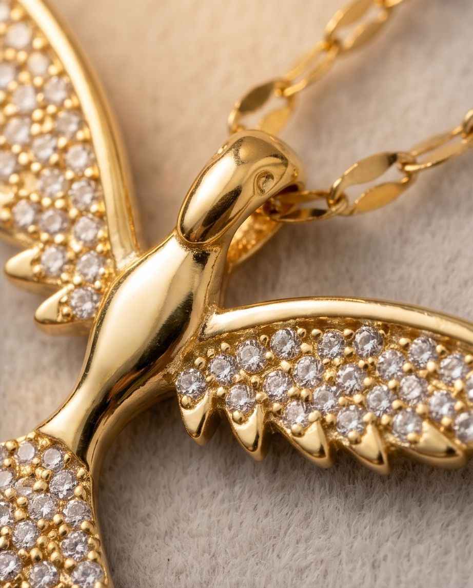 Gold bird pendant close-up with sparkling stone wings on fine-link chain