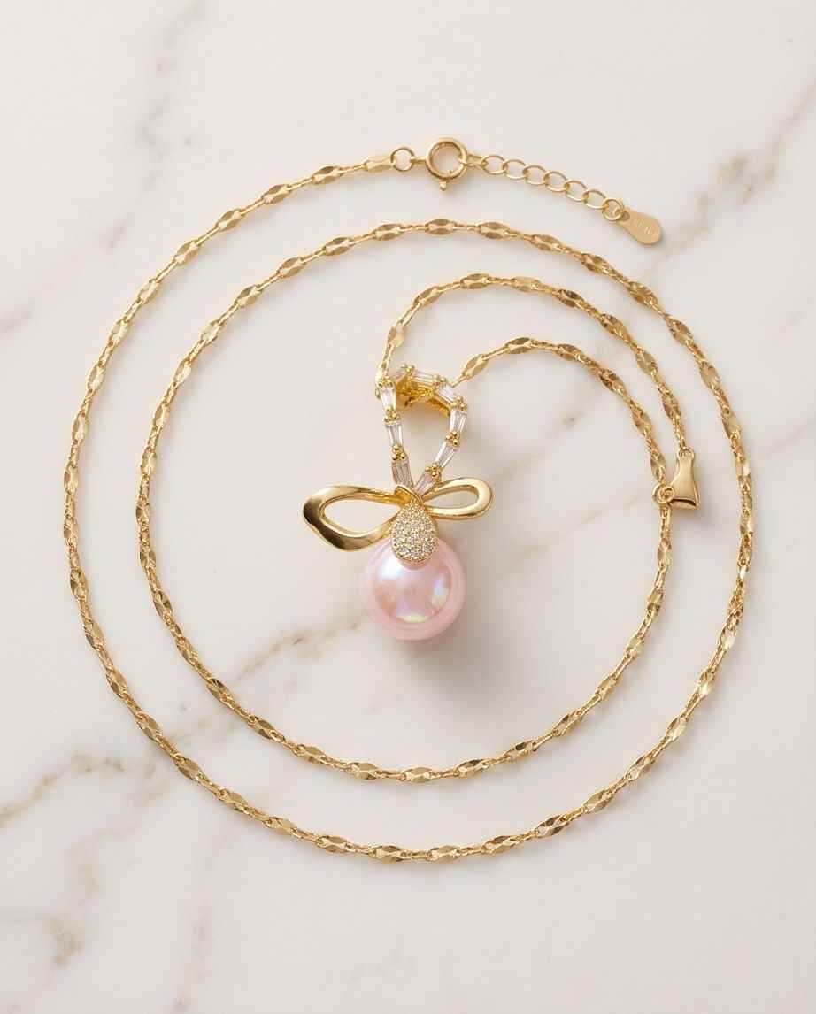 Gold bow pendant necklace with pink pearl drop and layered chains