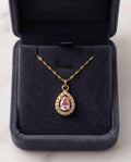 Gold pendant necklace with pink teardrop halo gemstone and small clear stones