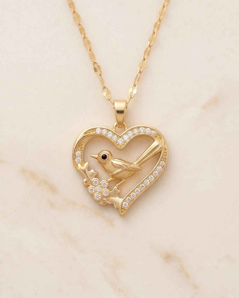 Gold heart pendant necklace with bird design and small crystal accents on chain