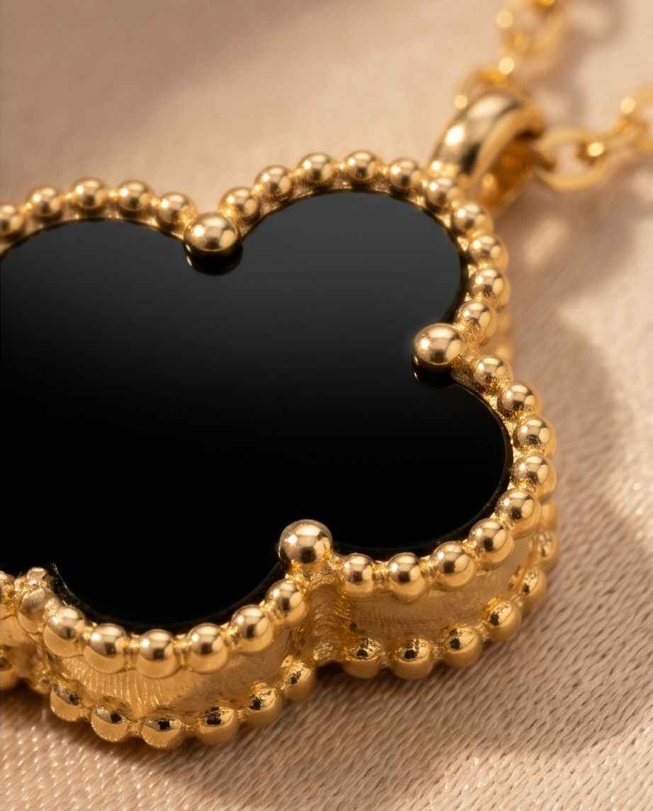 Gold clover pendant necklace close-up with black center and beaded frame