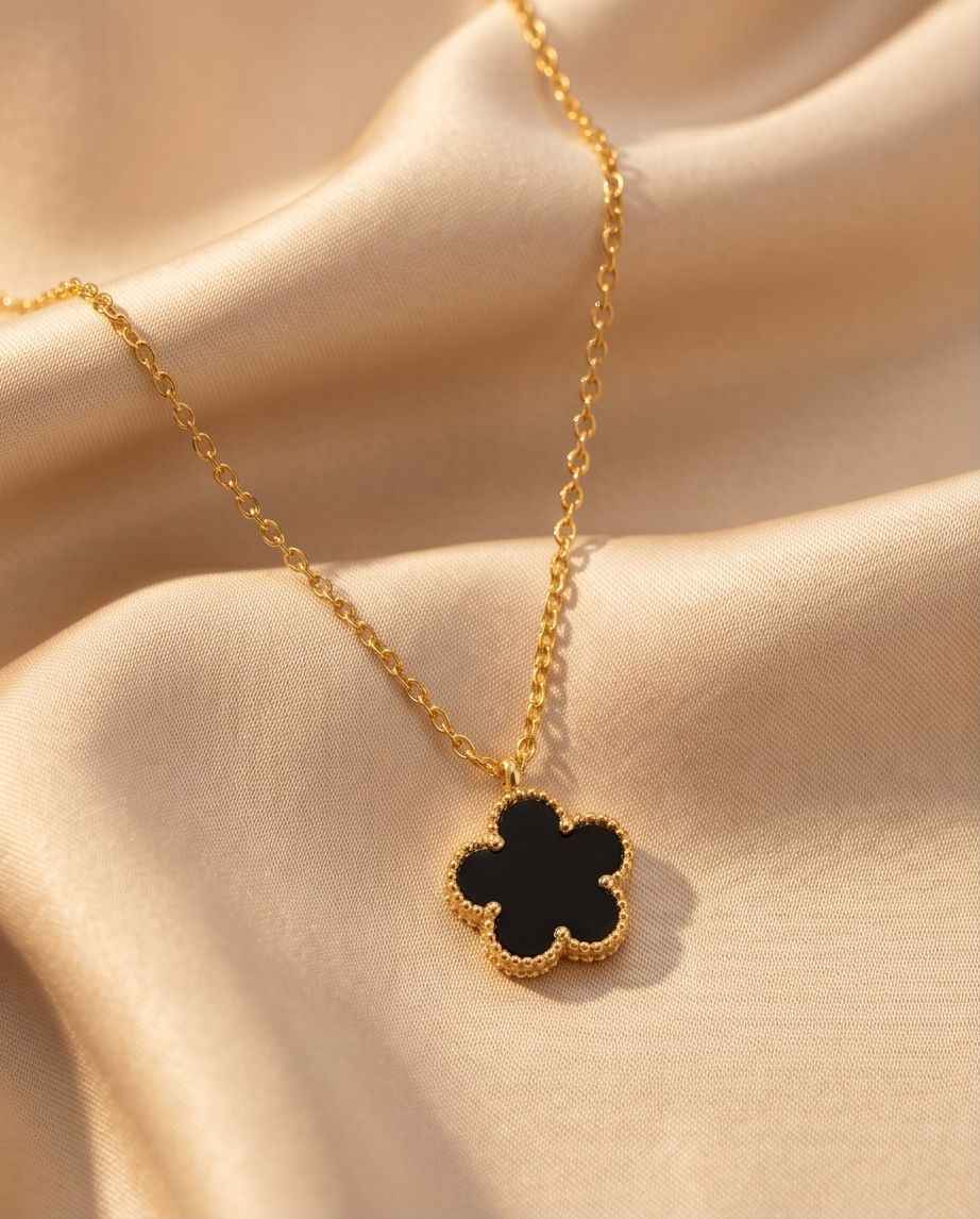 Gold clover pendant necklace with black four-leaf clover charm on chain