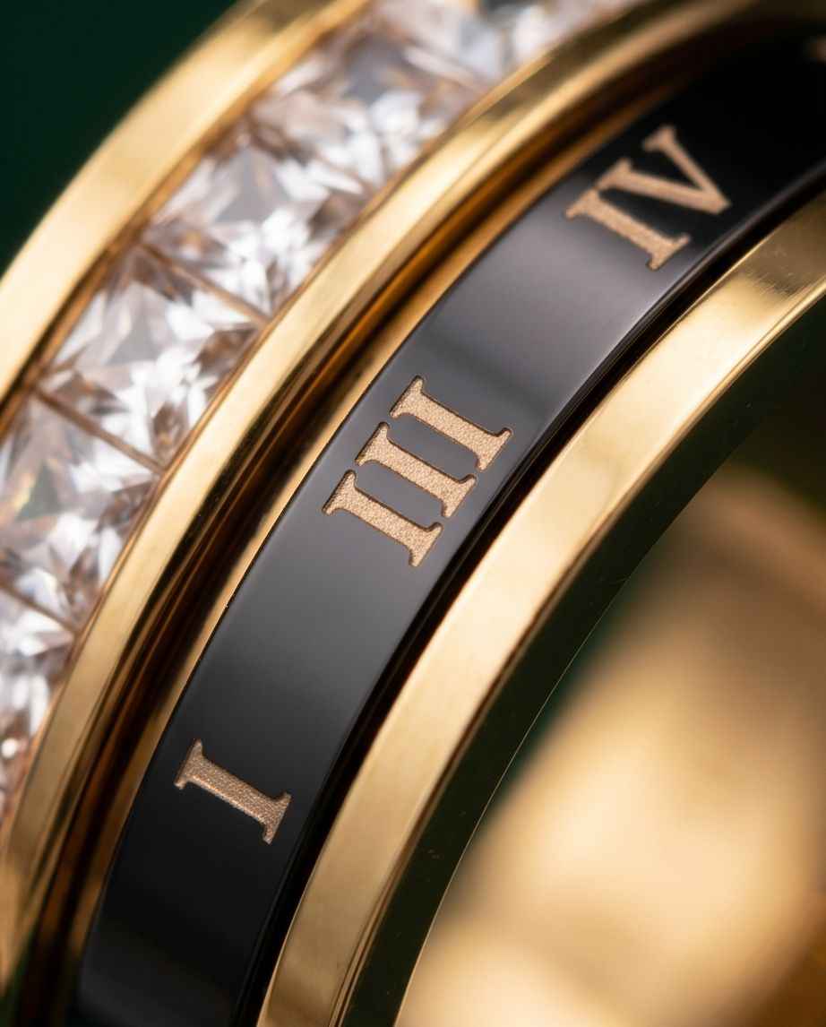 Gold-tone ring band close-up with Roman numerals and crystal stones