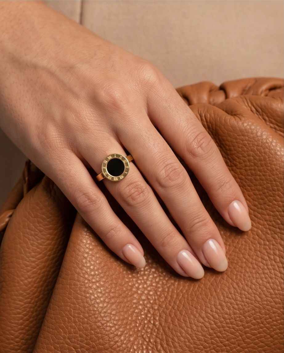 Gold ring on hand with black circular center and Roman numeral outer band