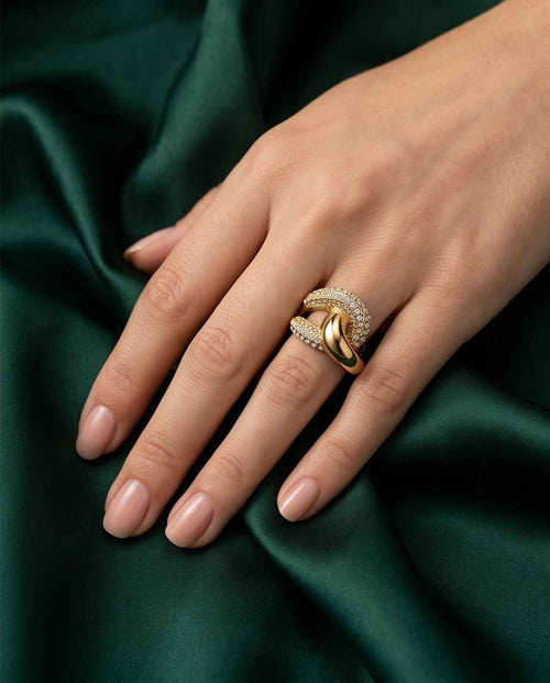 Gold-tone pavé crossover ring on finger, curved band with clear stones