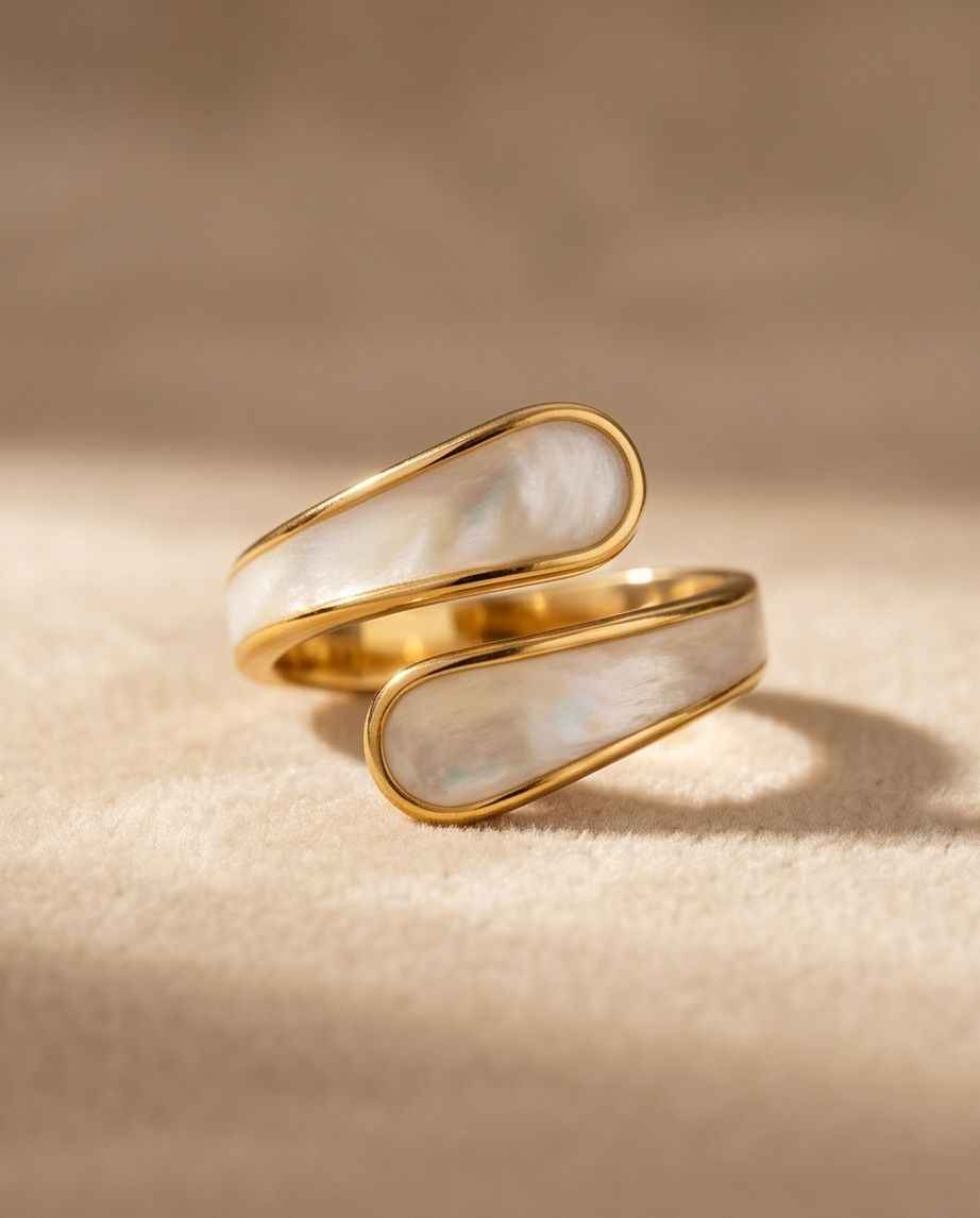 Gold crossover rings with white inlay, stacked on soft fabric
