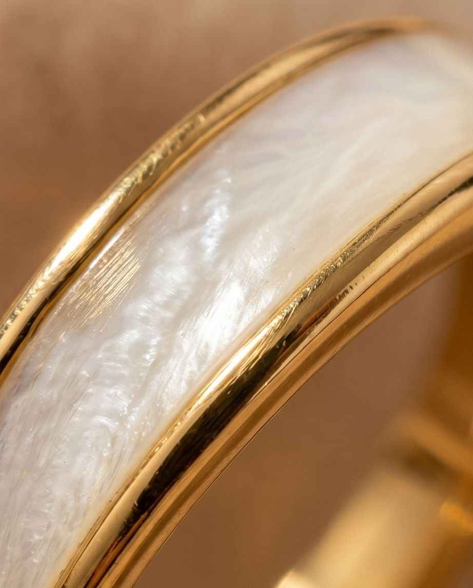 Close-up of gold crossover ring with glossy white inlay