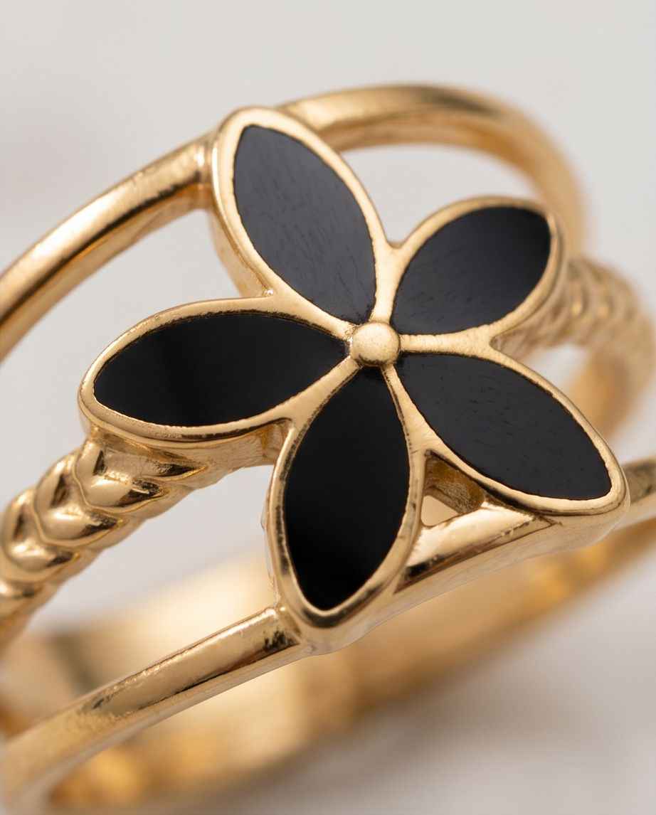 Close-up of gold open fleur ring with five black enamel petals and central dot