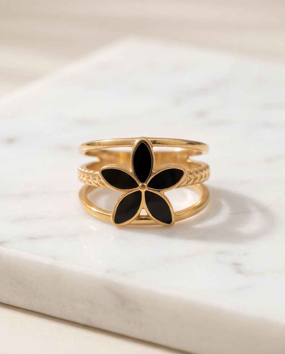 Gold open fleur ring with five black petal insets and ornate band texture