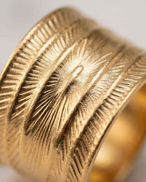 Gold textured ring band close-up with radial etched pattern and raised ridges