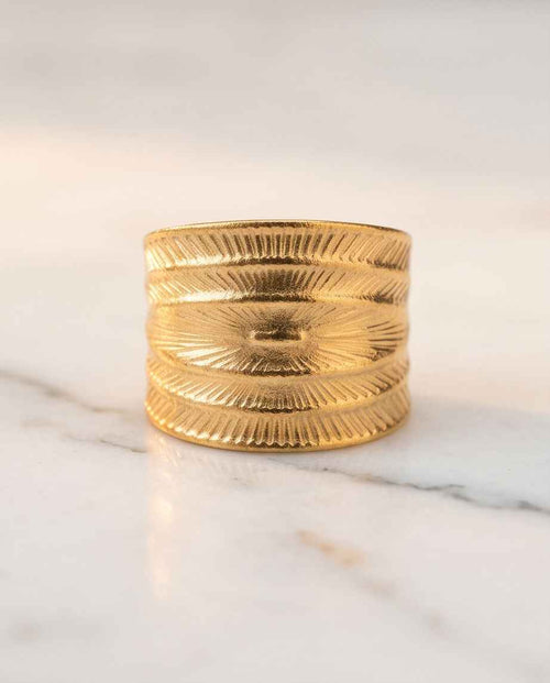 Gold textured statement ring with embossed sunburst and leaf-like grooves