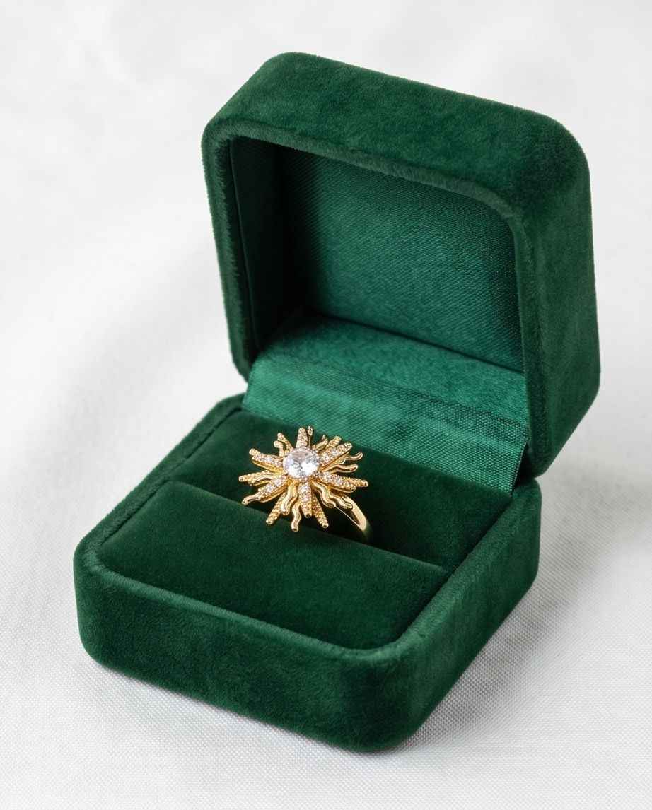 Gold statement ring with starburst cluster of clear stones, shown in green ring box