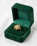 Gold statement ring with starburst cluster of clear stones, shown in green ring box