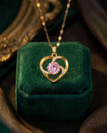 Gold heart pendant necklace with pink center gemstone and sparkling halo, on chain
