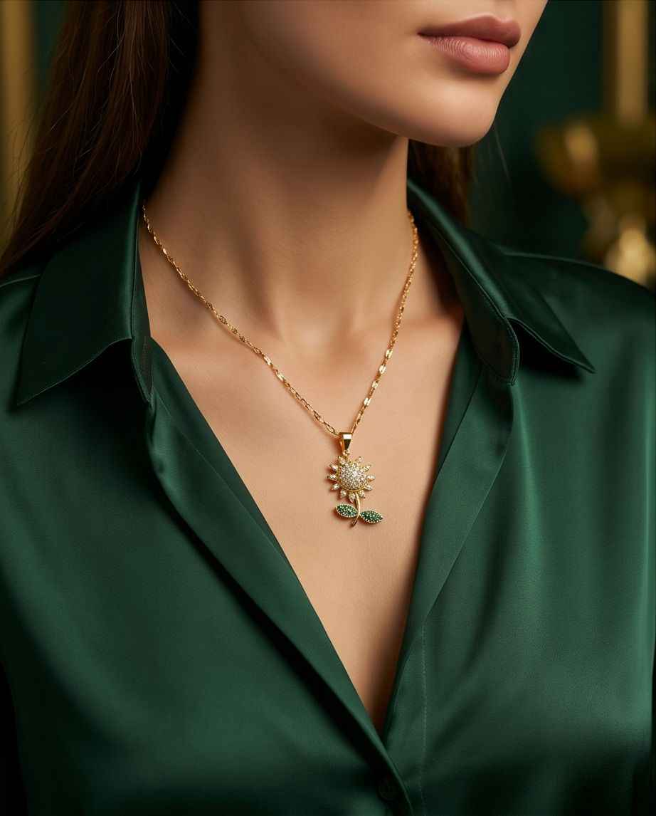 Gold-tone chain necklace with sunburst pendant and green leaf detail