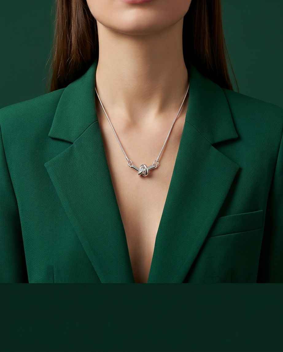 Silver twisted-knot pendant necklace worn with V-neck blazer
