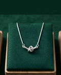 Silver necklace with twisted knot pendant and slender chain, lobster clasp visible