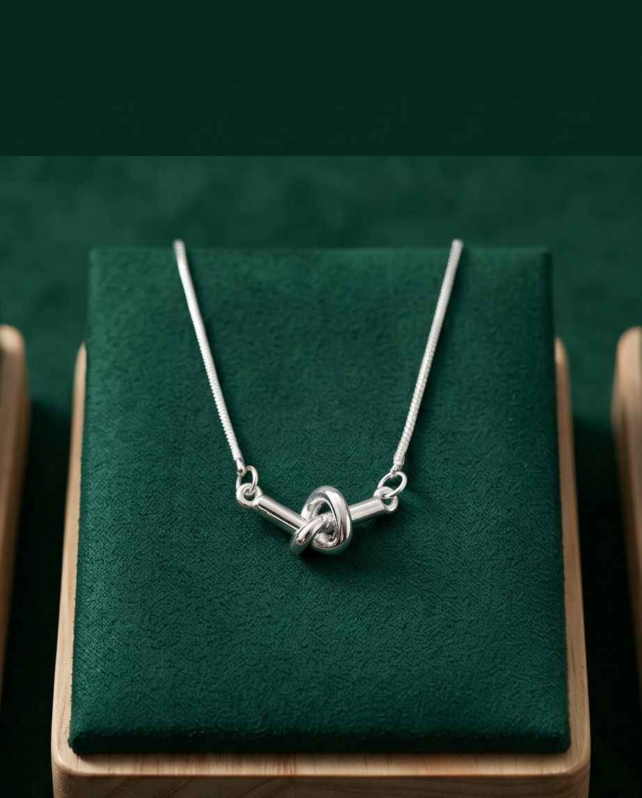 Silver necklace with twisted knot pendant and slender chain, lobster clasp visible
