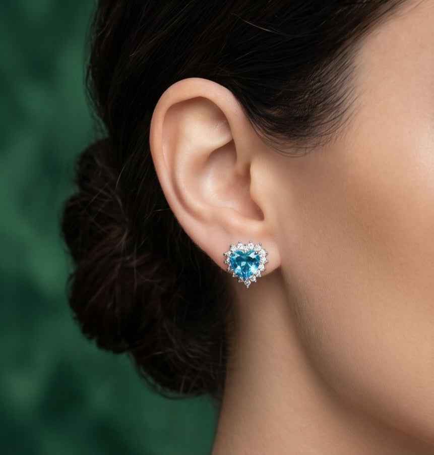 Blue heart halo stud earring on ear, silver-tone setting with clear stone halo