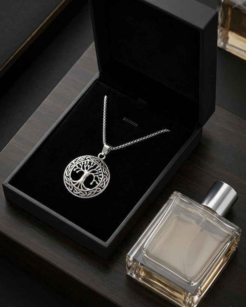Silver-toned round medallion necklace with tree-of-life design and chain in black box