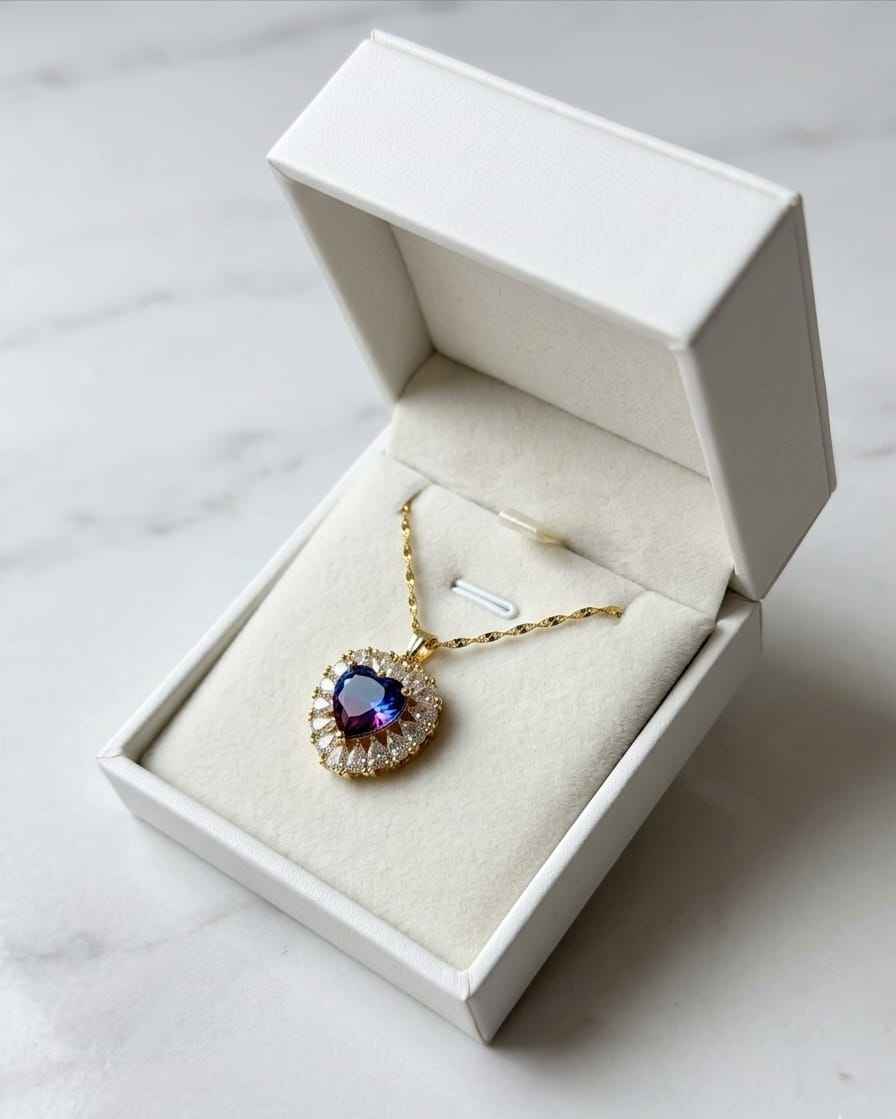Heart pendant necklace in a white gift box; gold-tone chain with blue crystal center