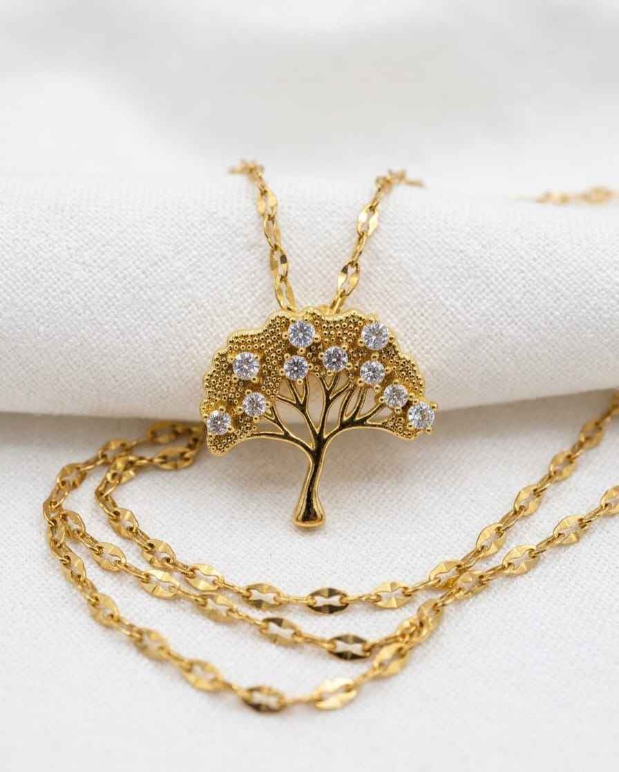 Gold-tone necklace with tree pendant and small round crystal accents, layered chain