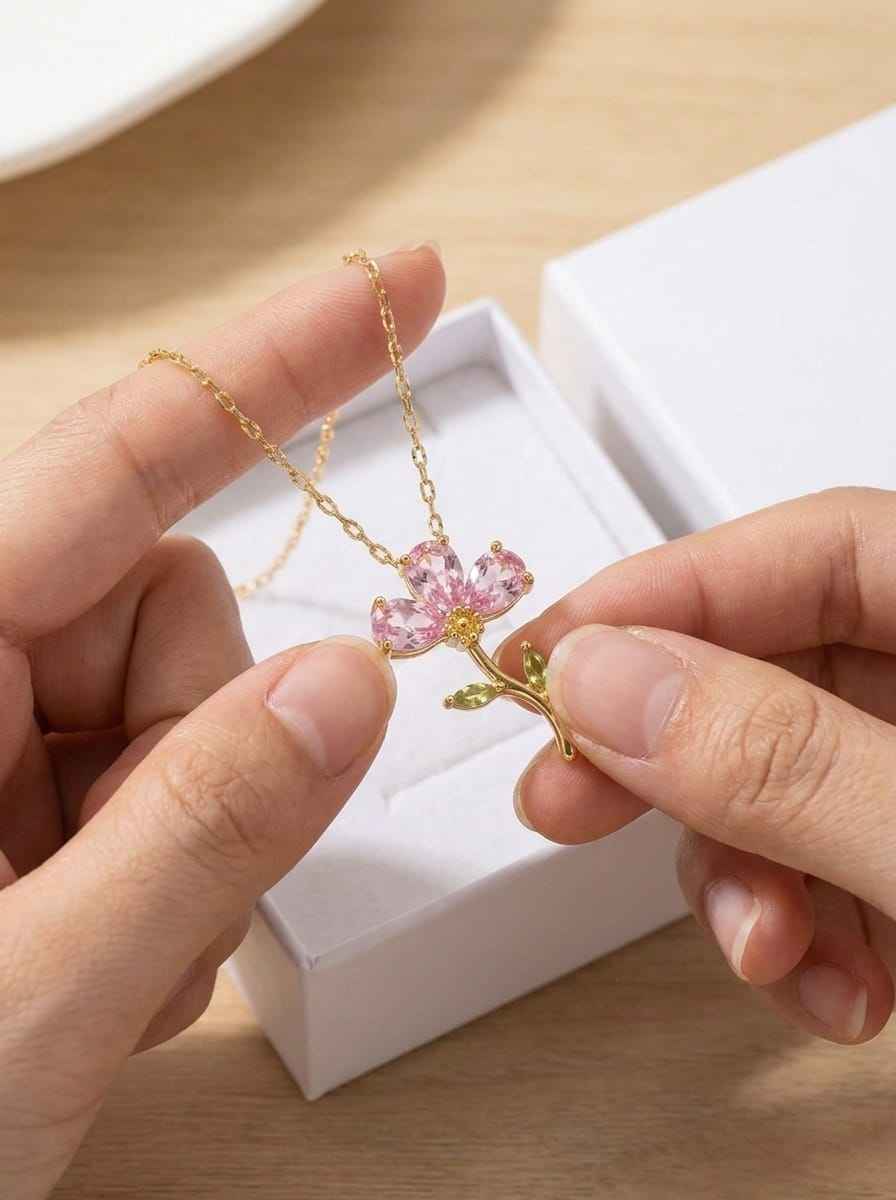 Gold tone crystal flower pendant necklace on chain with pink petals and green leaves