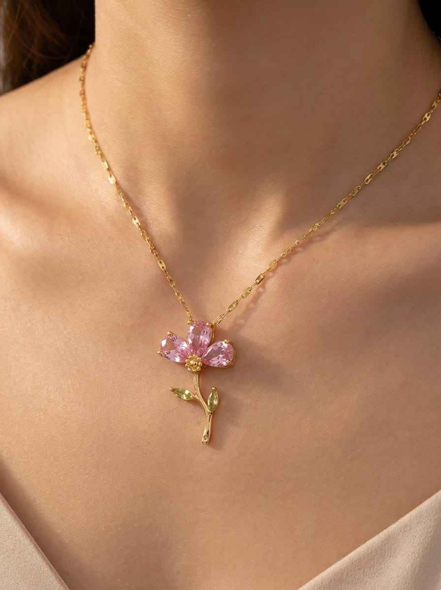 Gold tone crystal flower necklace with pink petals and green vine detail