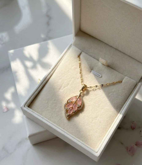 Gold-tone leaf pendant necklace with pink stone on chain, shown in gift box