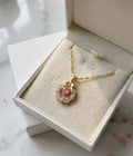 Gold-tone necklace with pink round pendant and clear stone halo