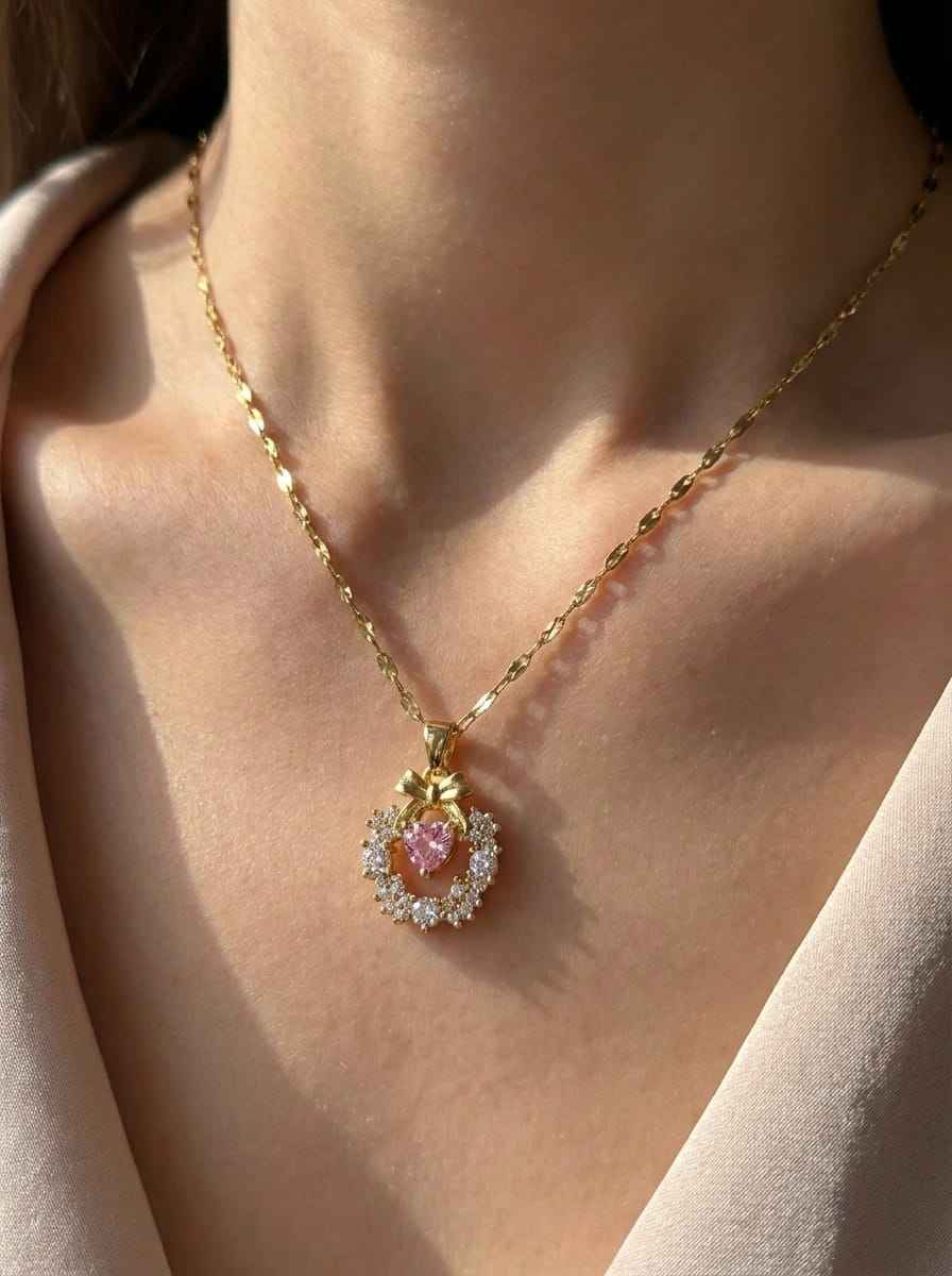 Gold-tone necklace featuring round pink pendant with clear halo on chain