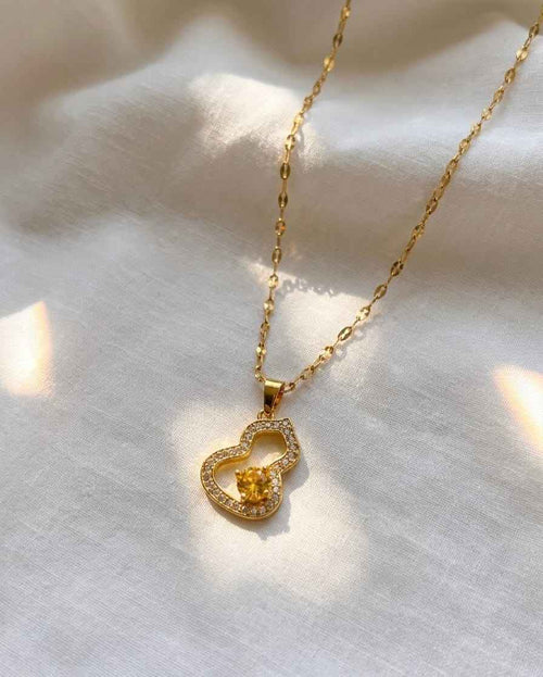 Gold-tone chain necklace with heart pendant and small yellow crystal center
