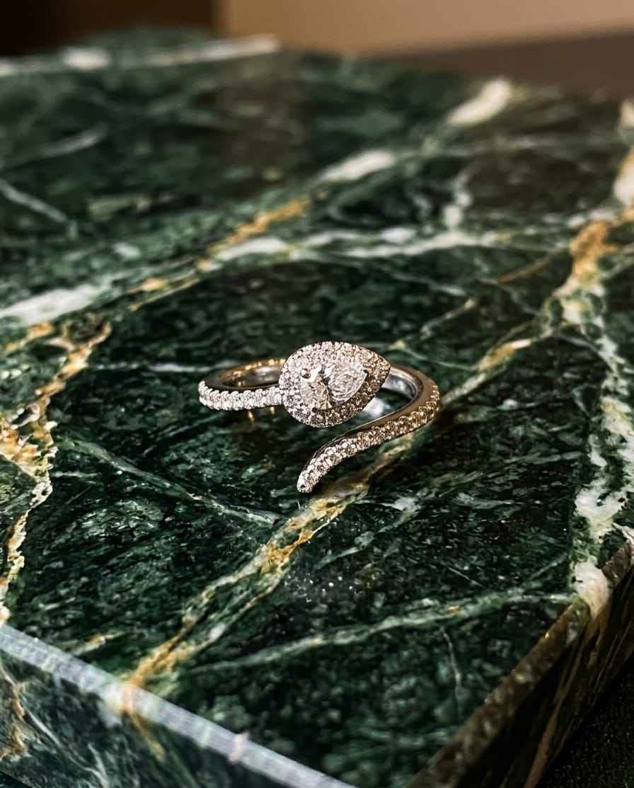 Pavé serpentine ring with teardrop halo center, viewed at an angle