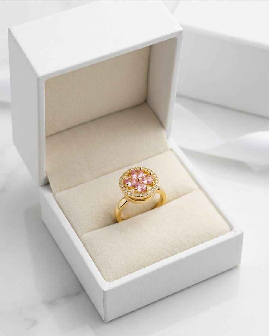 Gold halo ring with pink oval center stone and pavé band, shown in gift box
