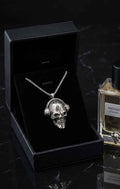 Silver-toned skull pendant necklace with twisted chain, shown in a gift box
