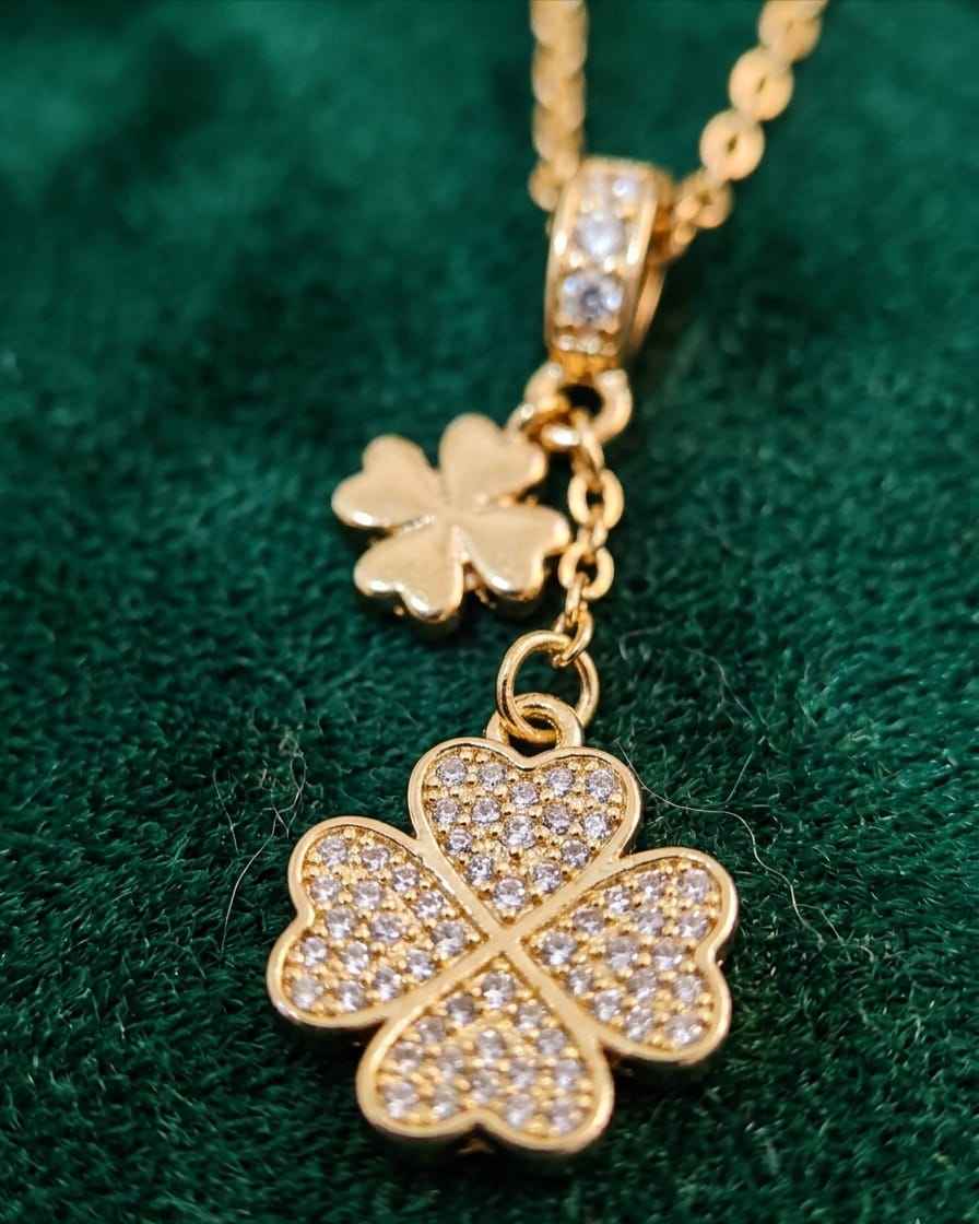 Gold clover drop necklace with pavé crystal detailing and dangling charm.
