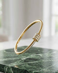Gold open bangle with pavé crystal accents and hinged clasp detail