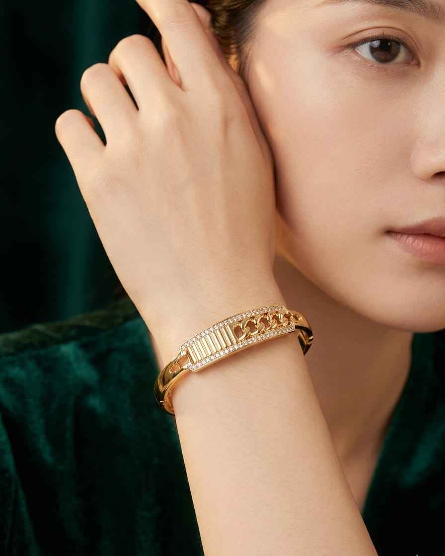 Gold textured bangle with pavé crystal accents, worn on wrist with ridged edge.