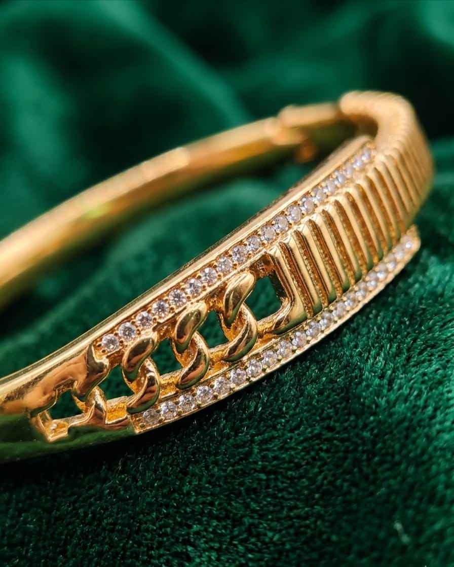 Close-up gold textured bangle with pavé crystals and raised chain link accents.