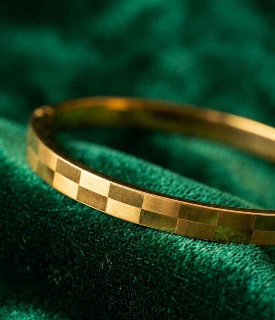 Gold faceted bangle bracelet with square-cut checker pattern, polished shine.