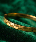 Gold faceted bangle bracelet with square-cut checker pattern, polished shine.