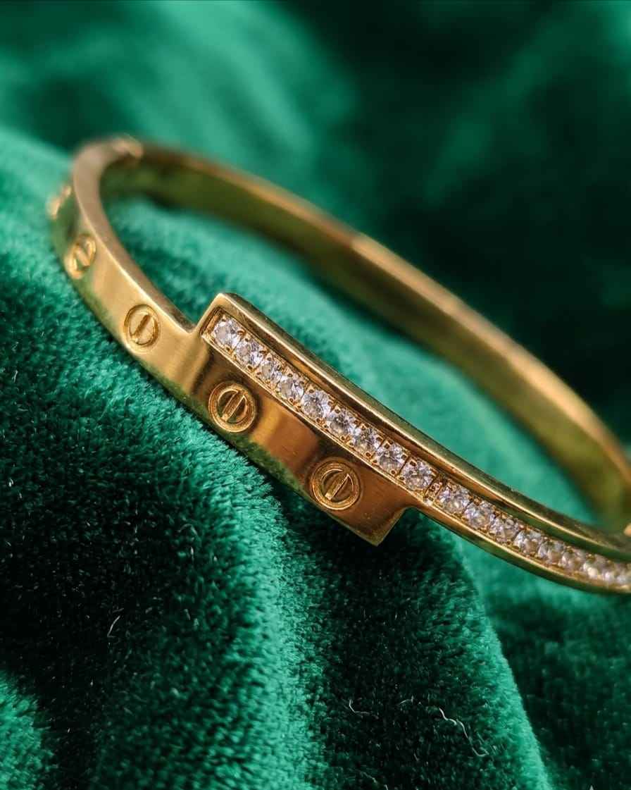 Close-up gold screw-motif bangle with pavé stone strip on textured fabric