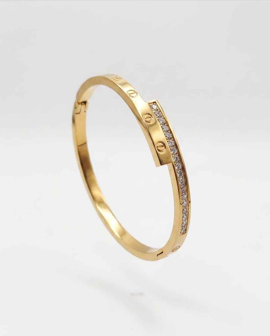 Gold screw-motif bangle with pavé stone detail, shown from the side
