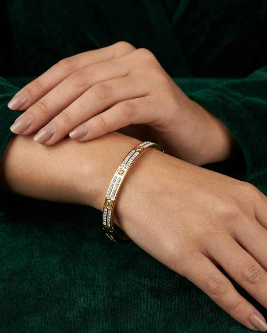 Gold-tone pavé link bangle with crystal-like stones and round emblem detail