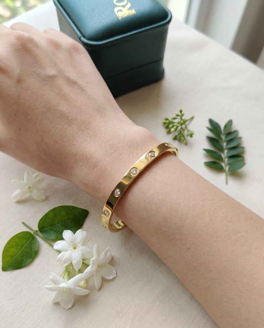 Gold bezel diamond bangle on wrist with round stones in a slim cuff