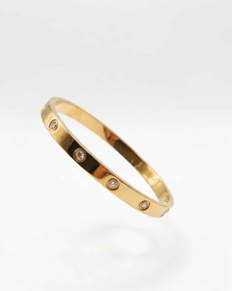 Gold diamond bangle with round bezel-set stones on a slim open cuff