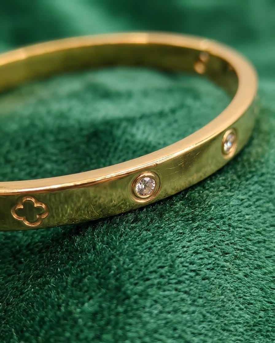 Gold clover bezel bangle close-up with crystal stones and clover cutout details