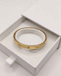 Gold clover bezel bangle with round crystal stones, shown in a gift box