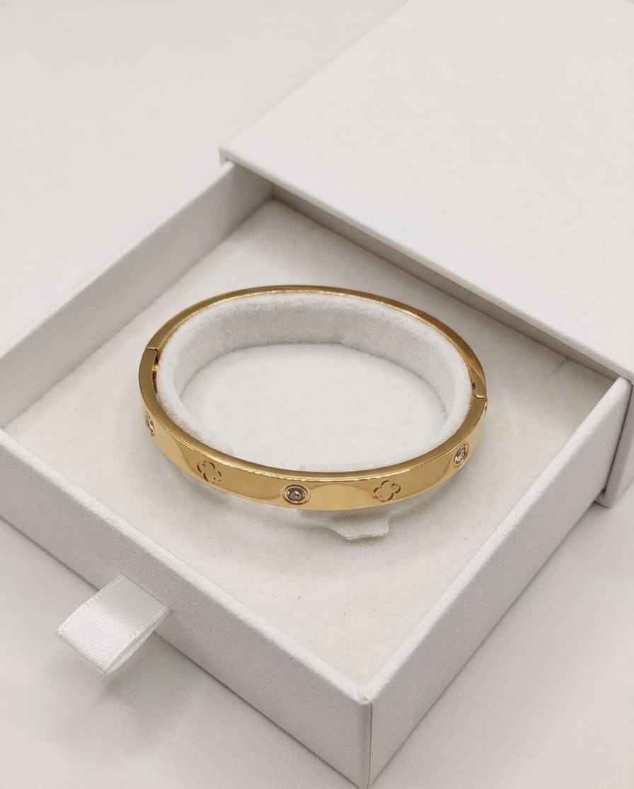 Gold clover bezel bangle with round crystal stones, shown in a gift box
